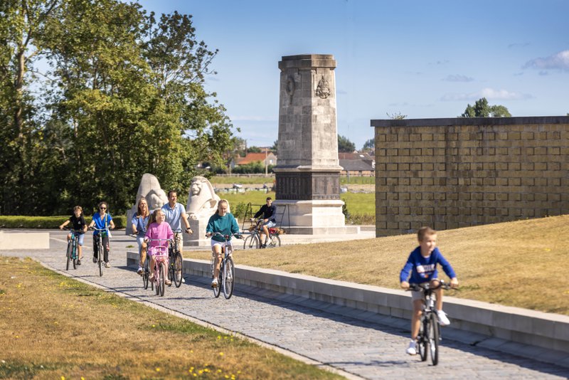 Familiefietsers op een fietspad in een park met toren op de achtergrond
