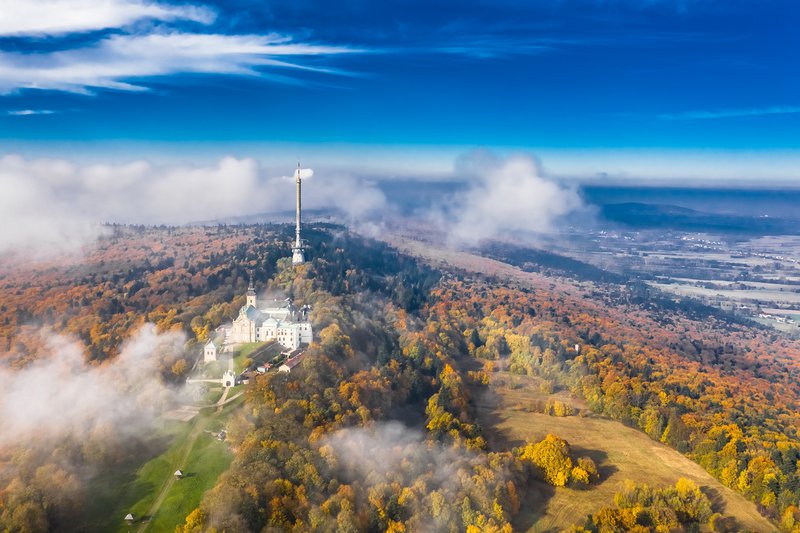Montagne entourée de verdure, avec une haute tour et un château au sommet.