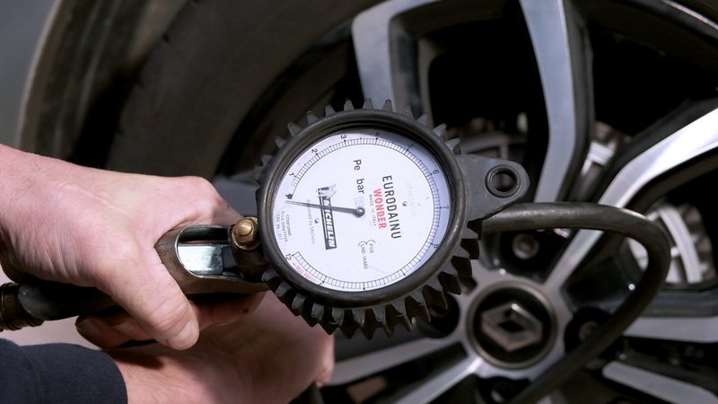 hand met manometer die bandenspanning meet
