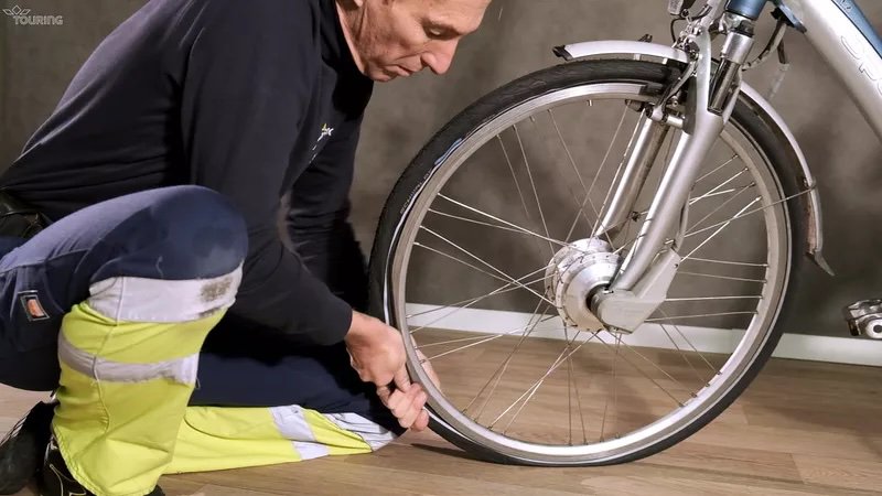 Un homme met une chambre à air dans le pneu de la roue avant d'un vélo.