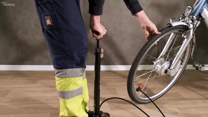 Un homme gonfle un pneu de vélo et vérifie s'il est suffisamment gonflé.
