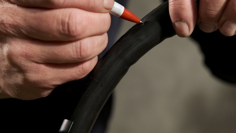Une main fait une marque au stylo sur une chambre à air de pneu de vélo.