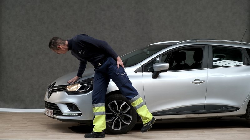 Un homme vérifie les phares d'une voiture.