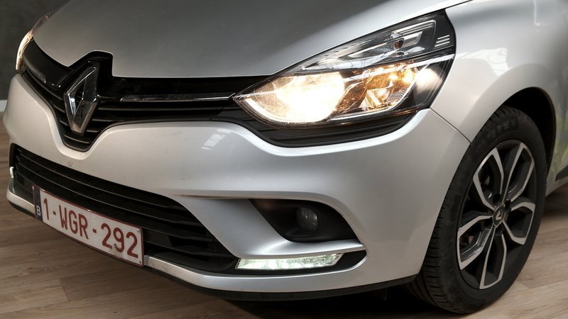 Les feux antibrouillard et les phares d'une voiture grise sont allumés