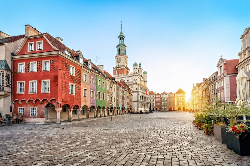 Une large rue pavée bordée de maisons colorées et de tours - Pologne