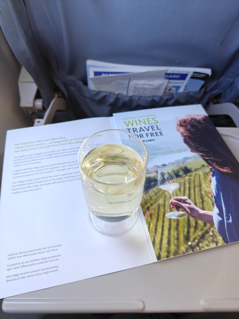 Verre de vin blanc posé sur une carte des vins à bord d'un vol SkyAlps.