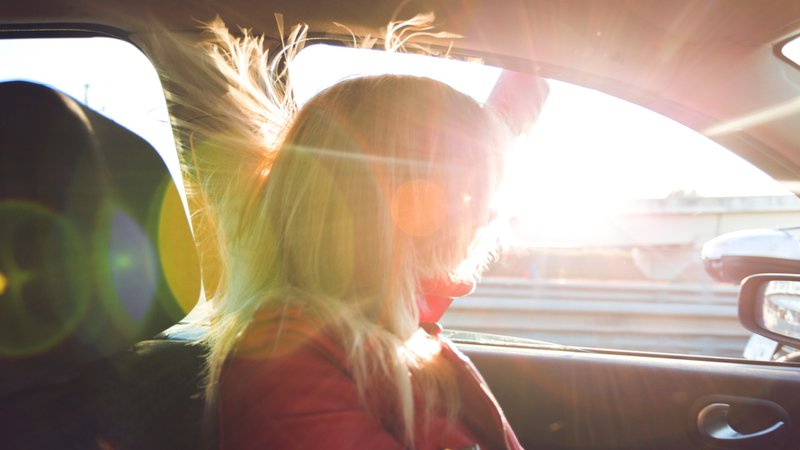 canicule, une femme au volant, vitre ouverte, les cheveux au vent.