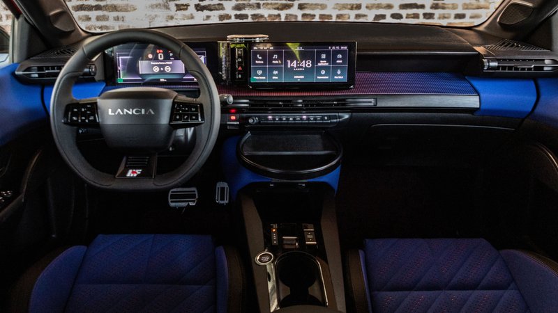 Habitacle de la Lancia Ypsilon HF avec volant sport, double écran numérique et sellerie bleue.